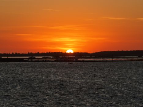 Stunning ocean sunset with vibrant orange hues reflecting over the water, creating a serene atmosphere.