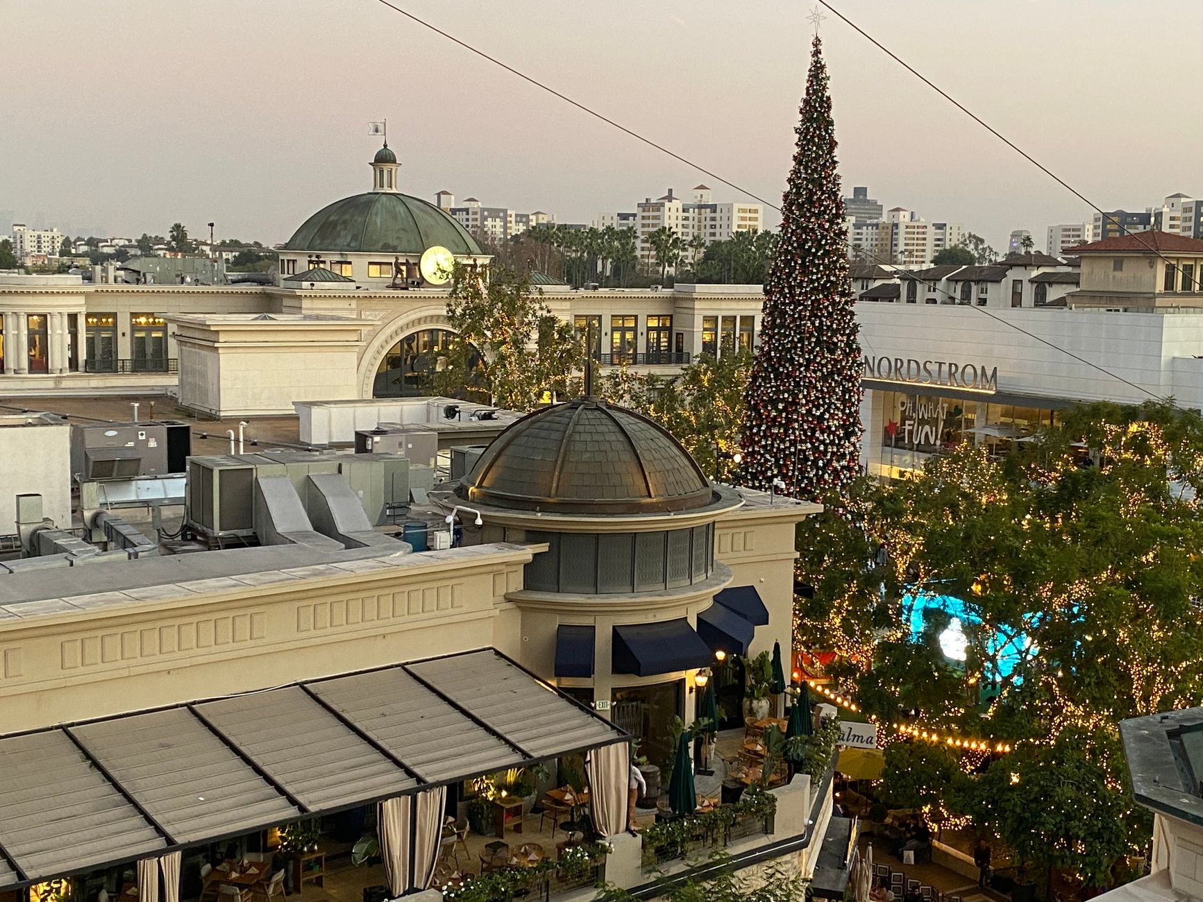 Aerial view of a decorated shopping mall with a Christmas tree at sunset.
