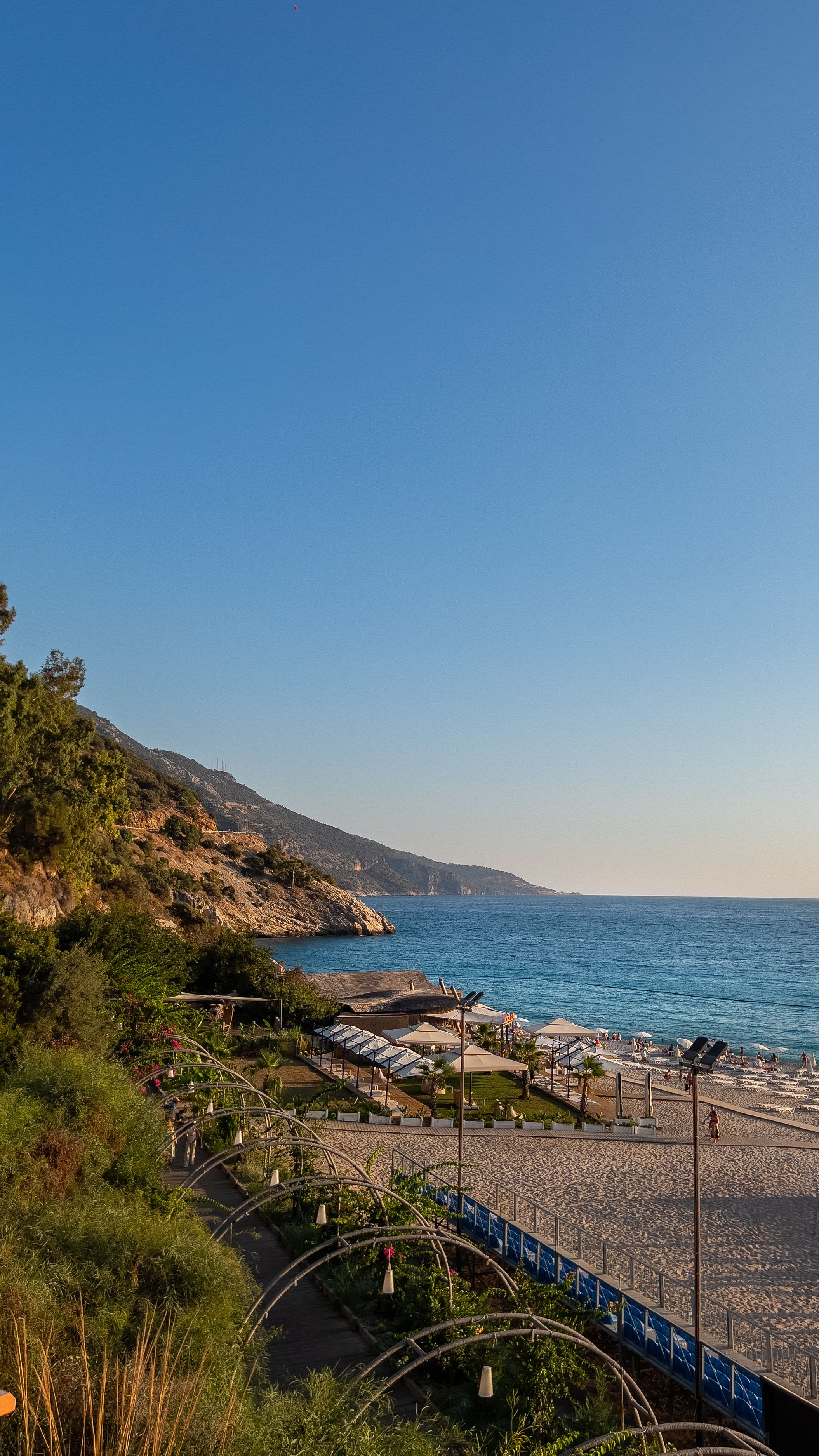 Relaxing beach scene at Ölüdeniz, Muğla, Türkiye with clear skies and blue waters.
