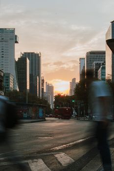 Sunset view of bustling Ciudad de México street with modern skyscrapers in the background.
