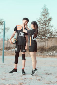 一对穿着运动服的年轻夫妇在户外打排球，享受着欢乐的时光