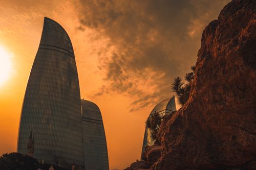 Free The iconic Flame Towers in Baku, Azerbaijan, silhouetted against a dramatic sunset sky. Stock Photo
