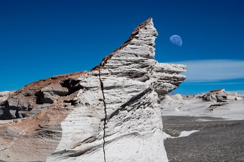 Free Breathtaking desert rock formations with the moon in a vivid blue sky. A perfect blend of nature's beauty and serenity. Stock Photo