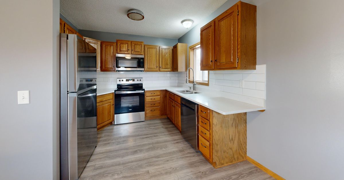 Spacious kitchen with wooden cabinets and stainless steel appliances.