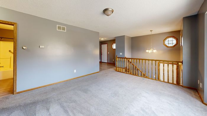 A bright, empty living room with carpet, wood accents, and natural light