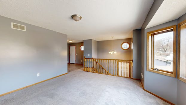 Bright and open interior with windows and staircase, ideal for real estate listings.
