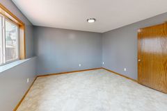 Spacious empty room with natural light from window and wooden door.