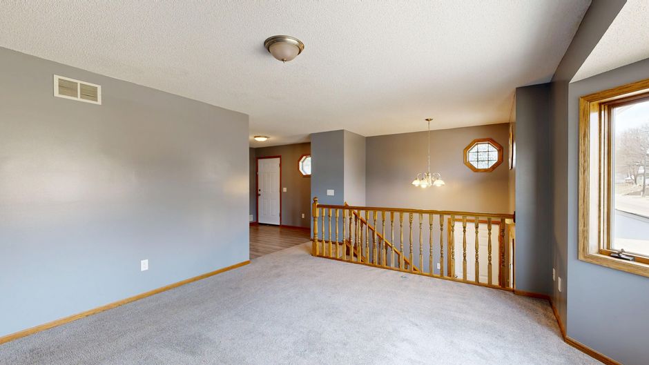 Spacious home interior featuring a staircase, carpet, windows, and neutral tones.