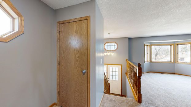 Bright interior with staircase and large windows, showcasing a cozy home atmosphere.