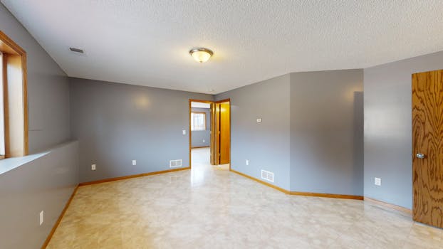 Bright empty room with gray walls, wooden trim, and a single light fixture.