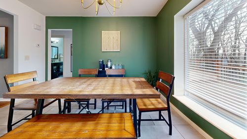 Free Bright dining room with wooden table, chairs, and green accent wall illuminated by natural light. Stock Photo