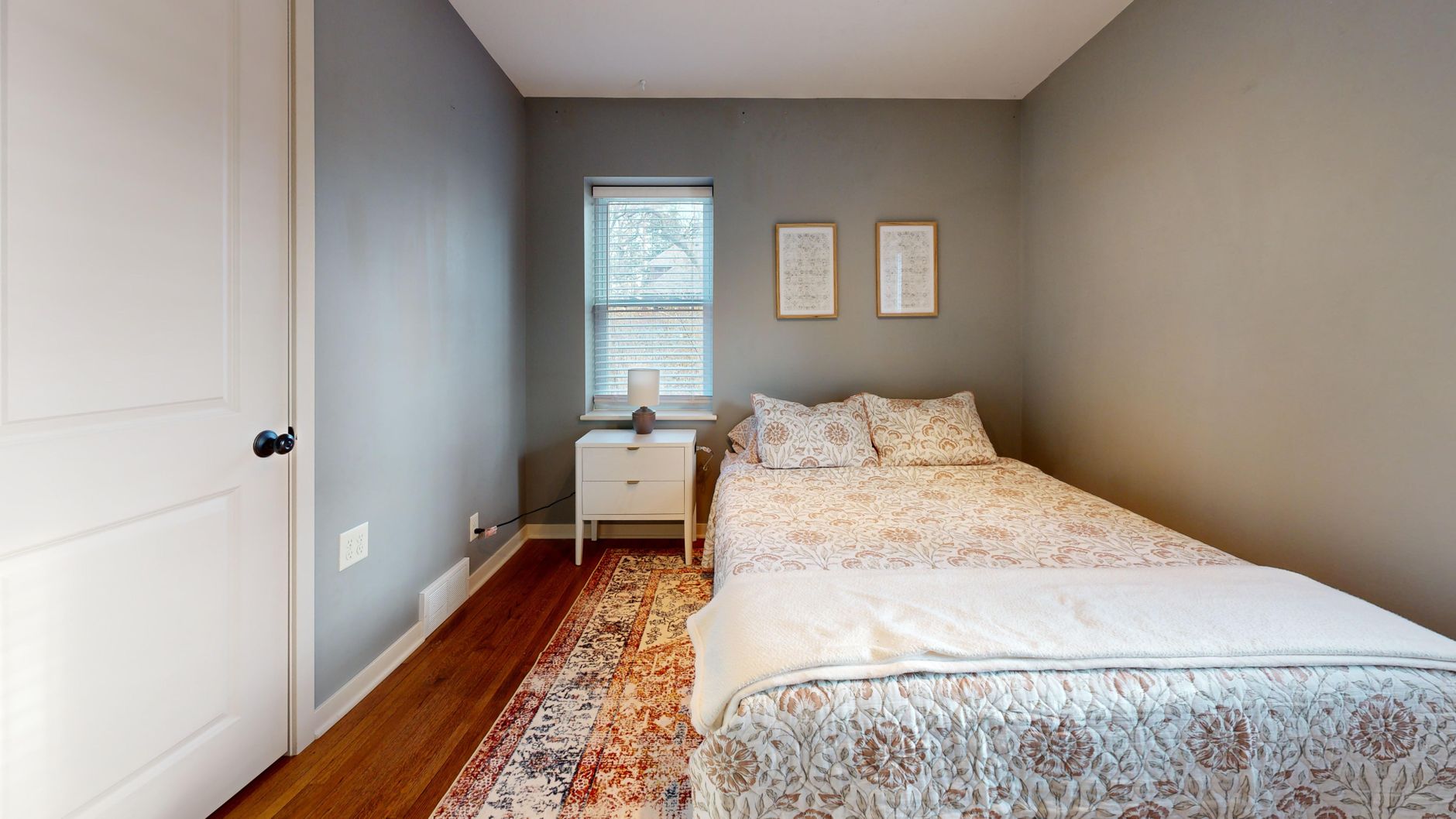 A serene minimalist bedroom with cozy bedding and natural light from a window.