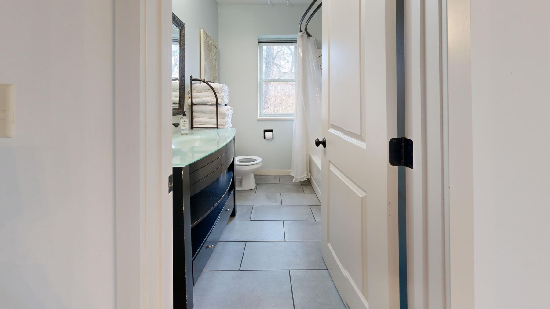 Bright modern bathroom with a large window, pale surfaces and a clear uncluttered layout