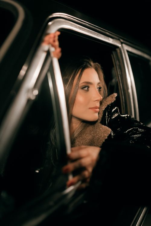 Free Elegant woman in a car at night, captured with moody, dramatic lighting showcasing a fashionable look. Stock Photo