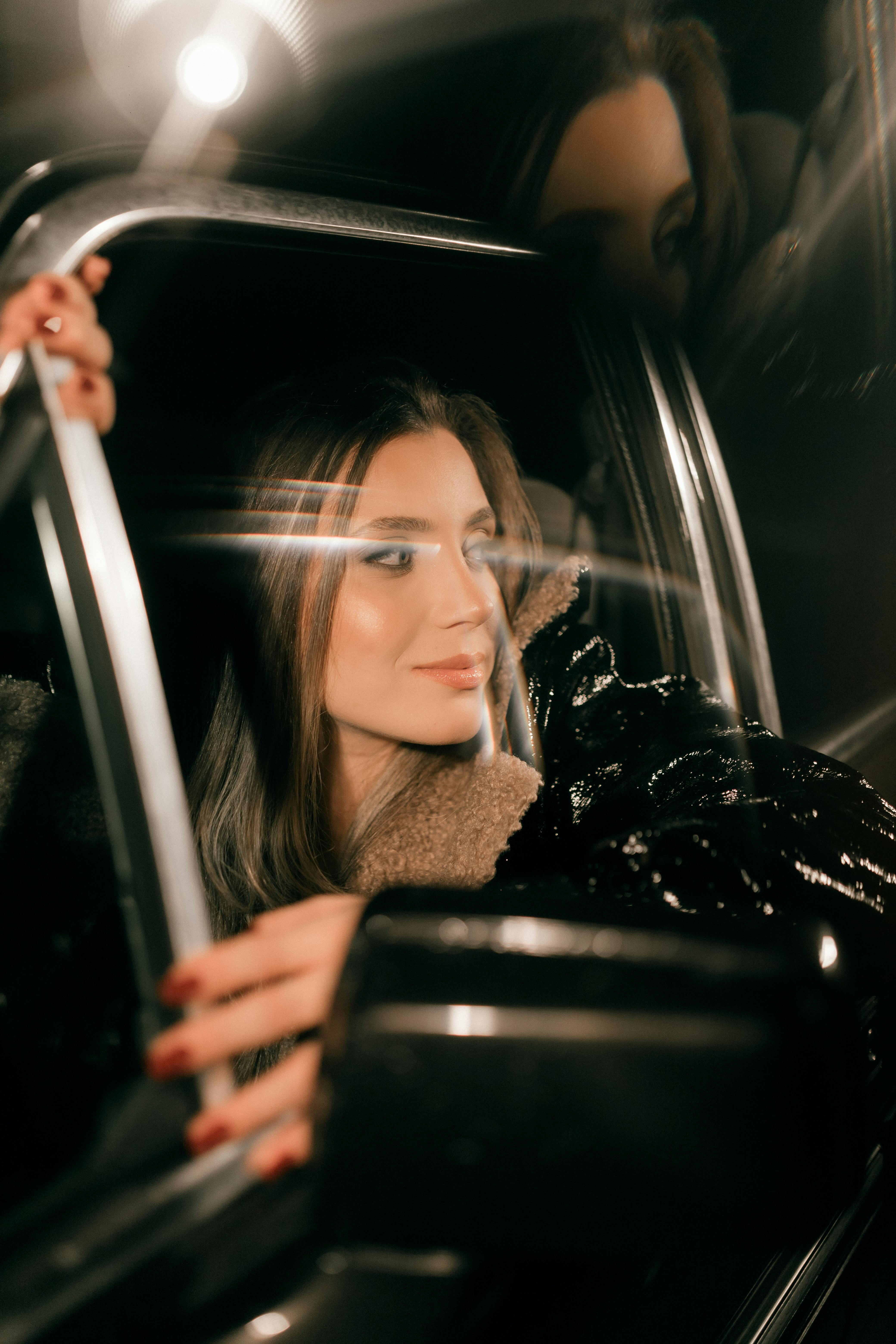 A fashionable woman looks out from a car window at night, exuding glamour and elegance.