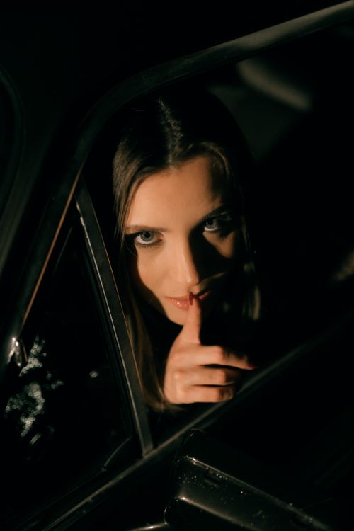 Free A woman in a car at night with a secretive expression in low light. Stock Photo