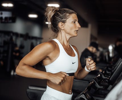 Fit woman exercising on a treadmill in a modern gym setting.