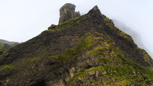 Free A breathtaking foggy mountain peak known for its rugged texture and lush green patches. Stock Photo