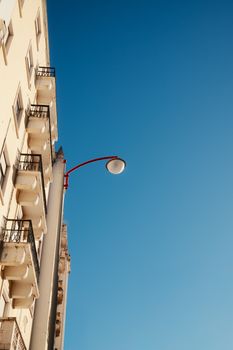 Upward view of a Lisbon building facade with a vibrant blue sky and streetlamp, showcasing European architecture.