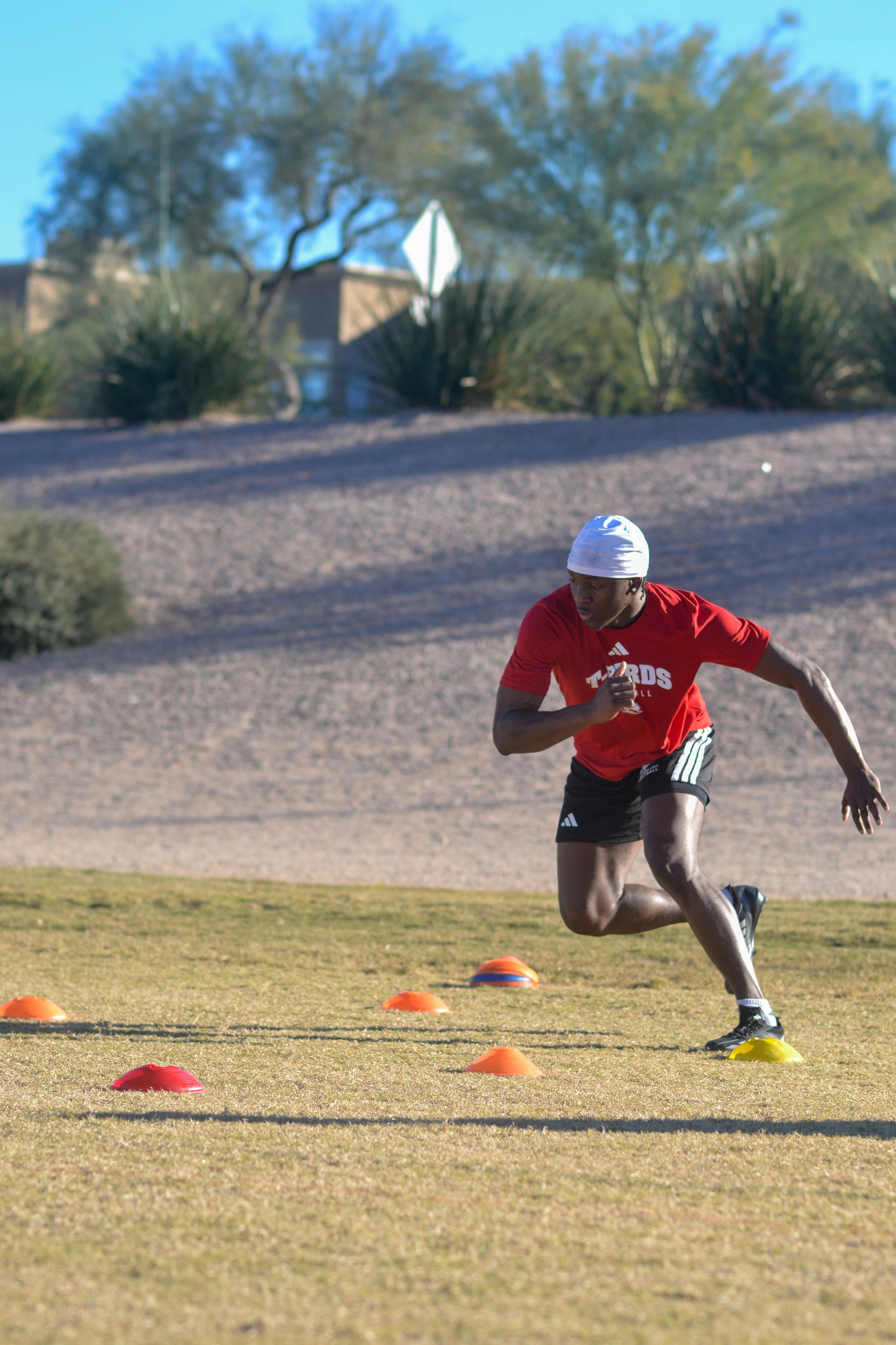 A young man practices sprinting drills outdoors in Scottsdale, Arizona under a clear sky.