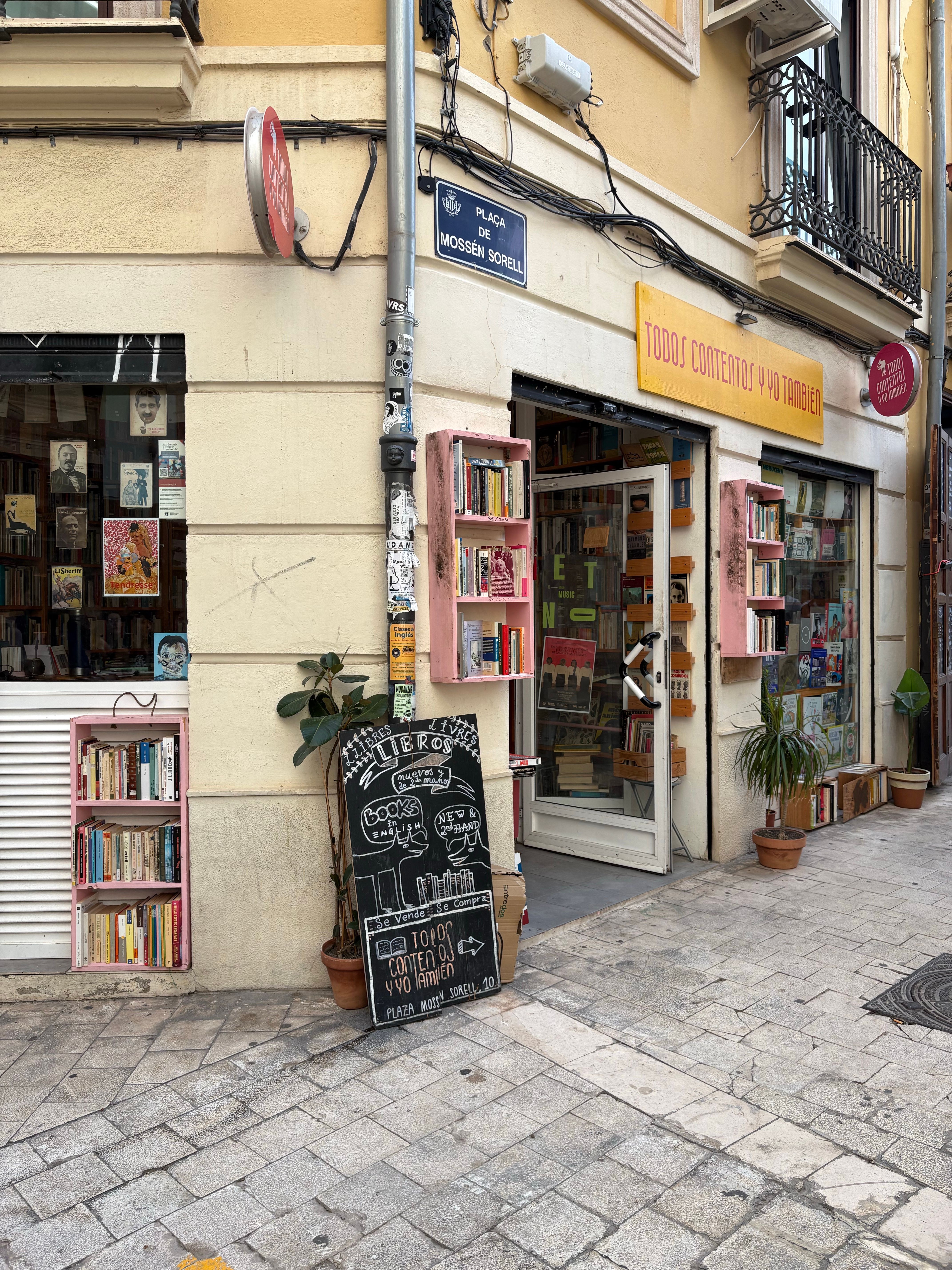 Explore a quaint bookstore in Valencia, Spain, with street displays and vibrant facade.