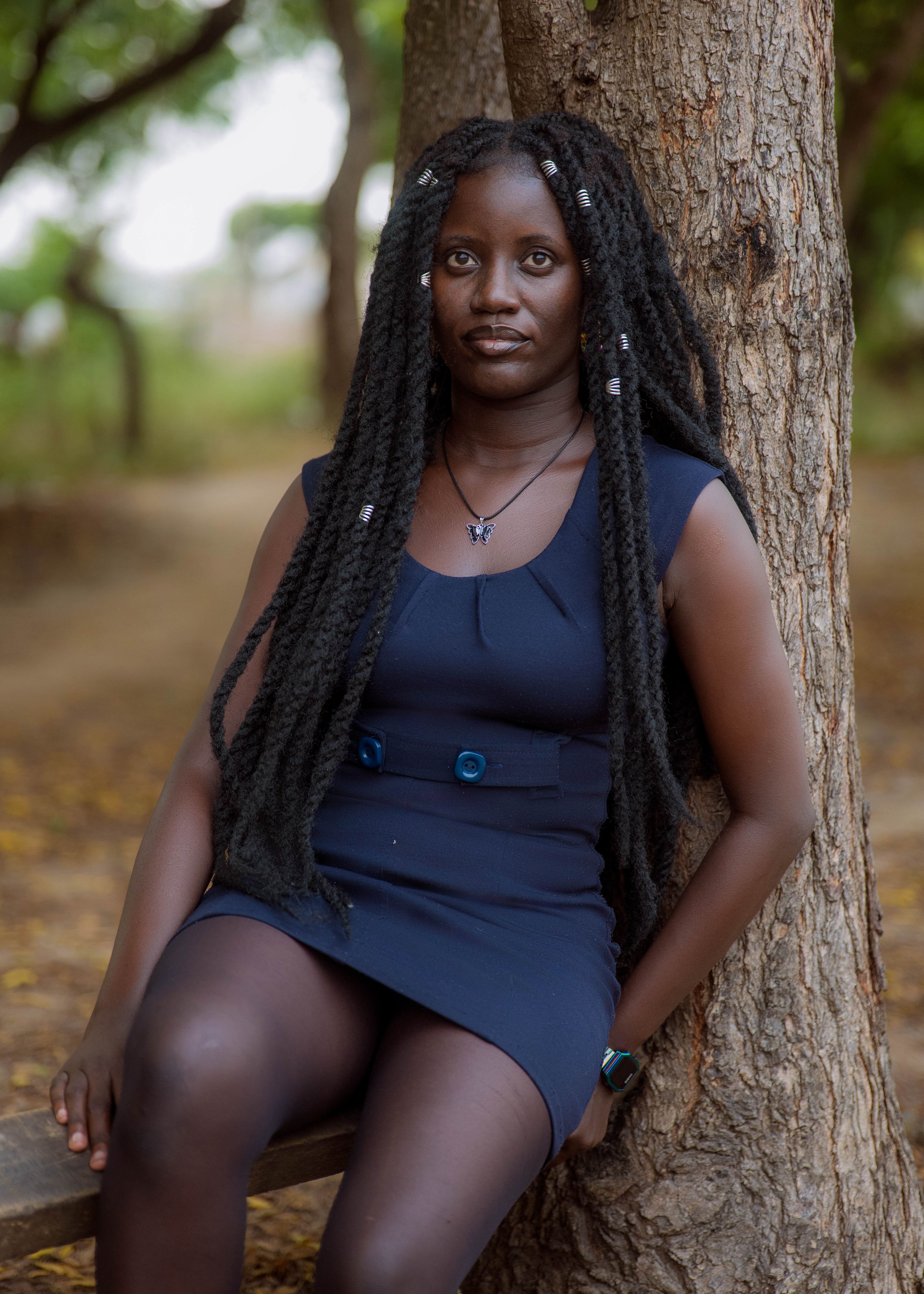 Casual portrait of a woman leaning against a tree outdoors, showcasing natural beauty and serene expression.