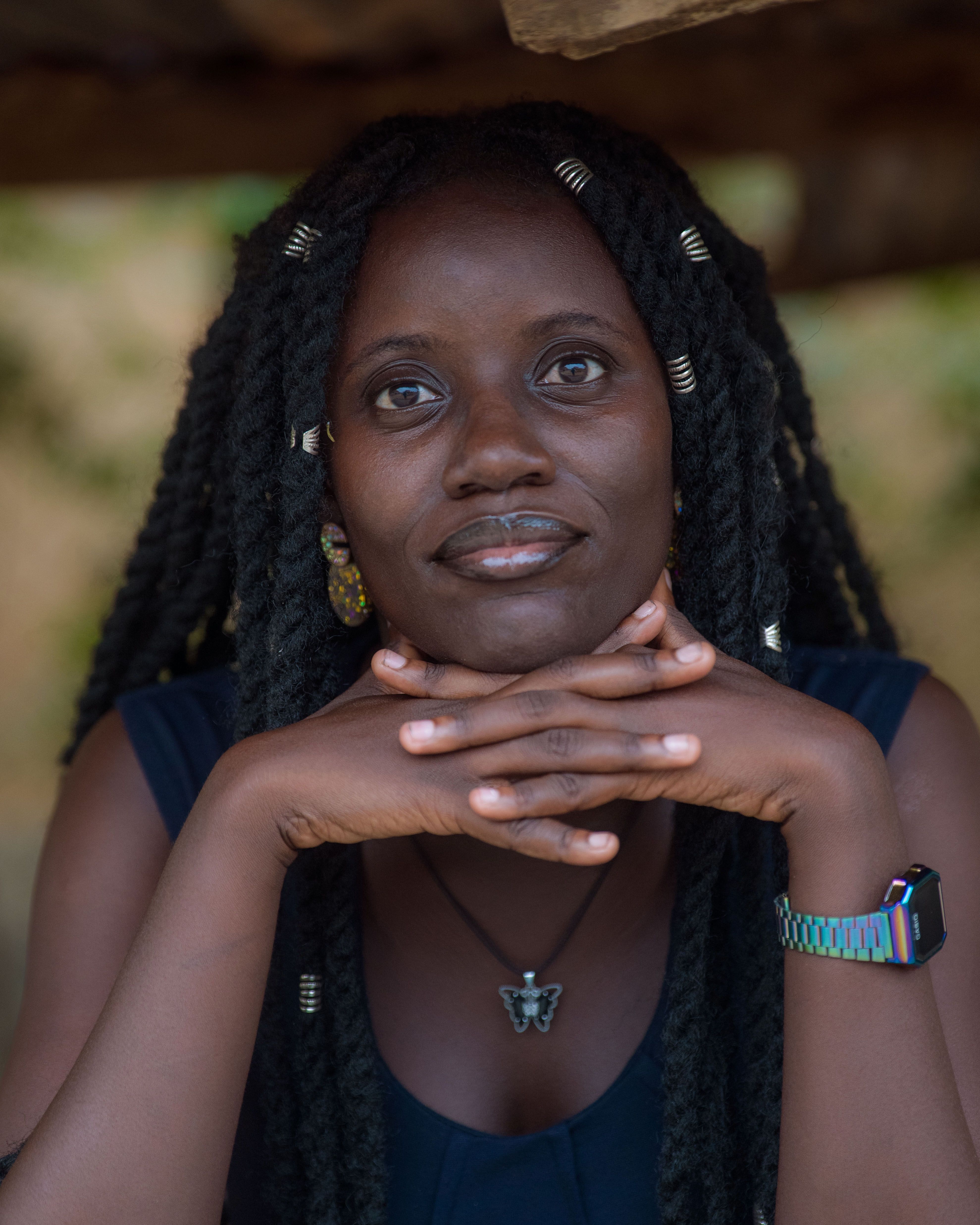Expressive portrait of a woman resting her chin on folded hands outdoors.