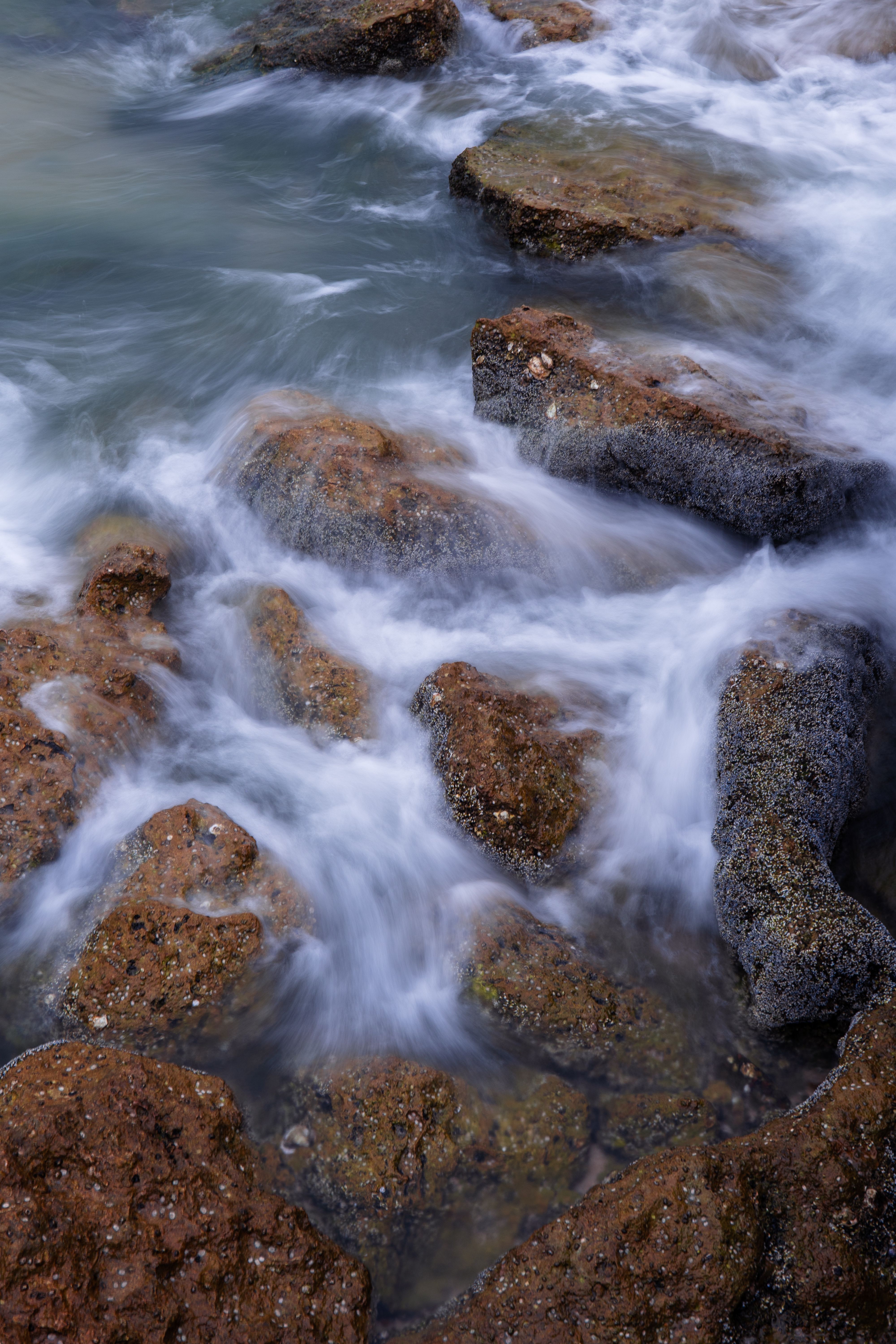 Captivating long exposure photo of ocean waves crashing over rocks in Al Ahmadi Governorate, Kuwait.