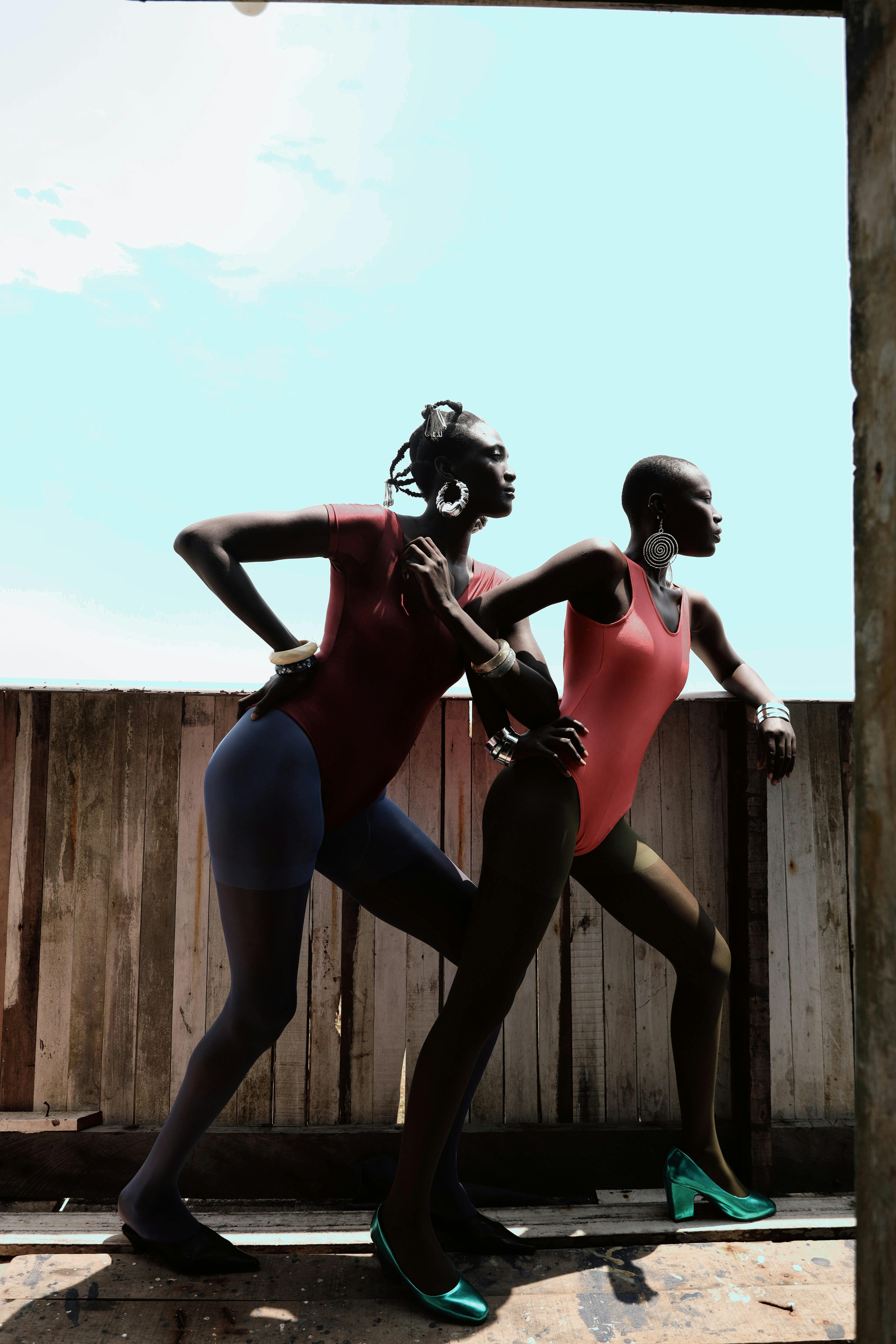 Zadarmo Dve modelky dynamicky pózujú vonku vo farebných outfitoch a predvádzajú odvážnu módu. Fotka z fotobanky