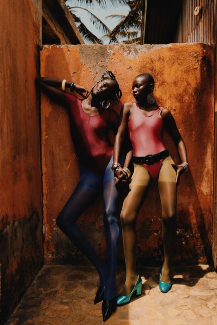 Striking image of two models in vibrant fashion posing against textured wall.
