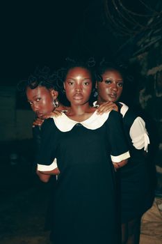 Chic nighttime portrait of three women with braided hairstyles and black dresses.