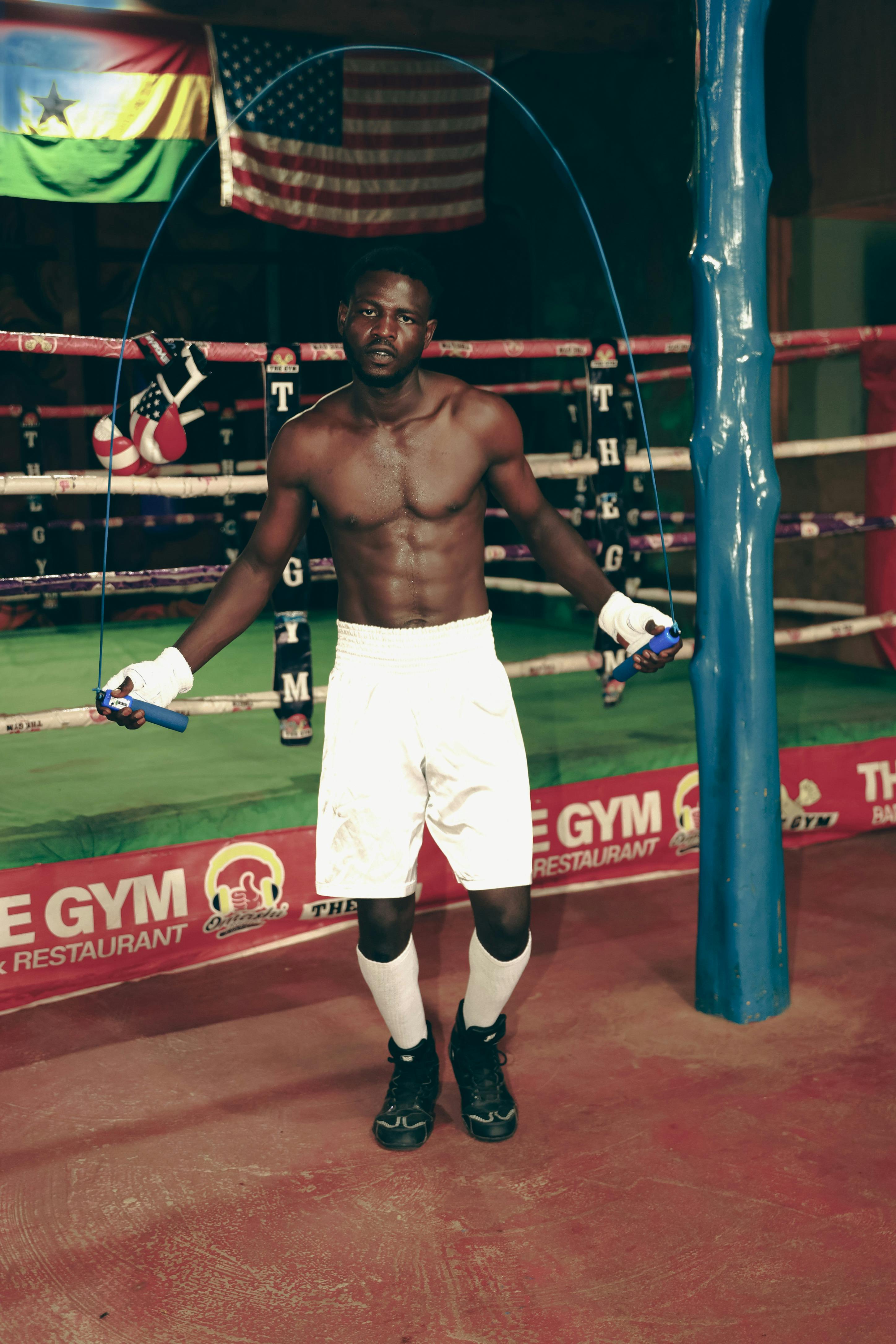 Fit young boxer skipping rope in a gym, showcasing strength and focus.