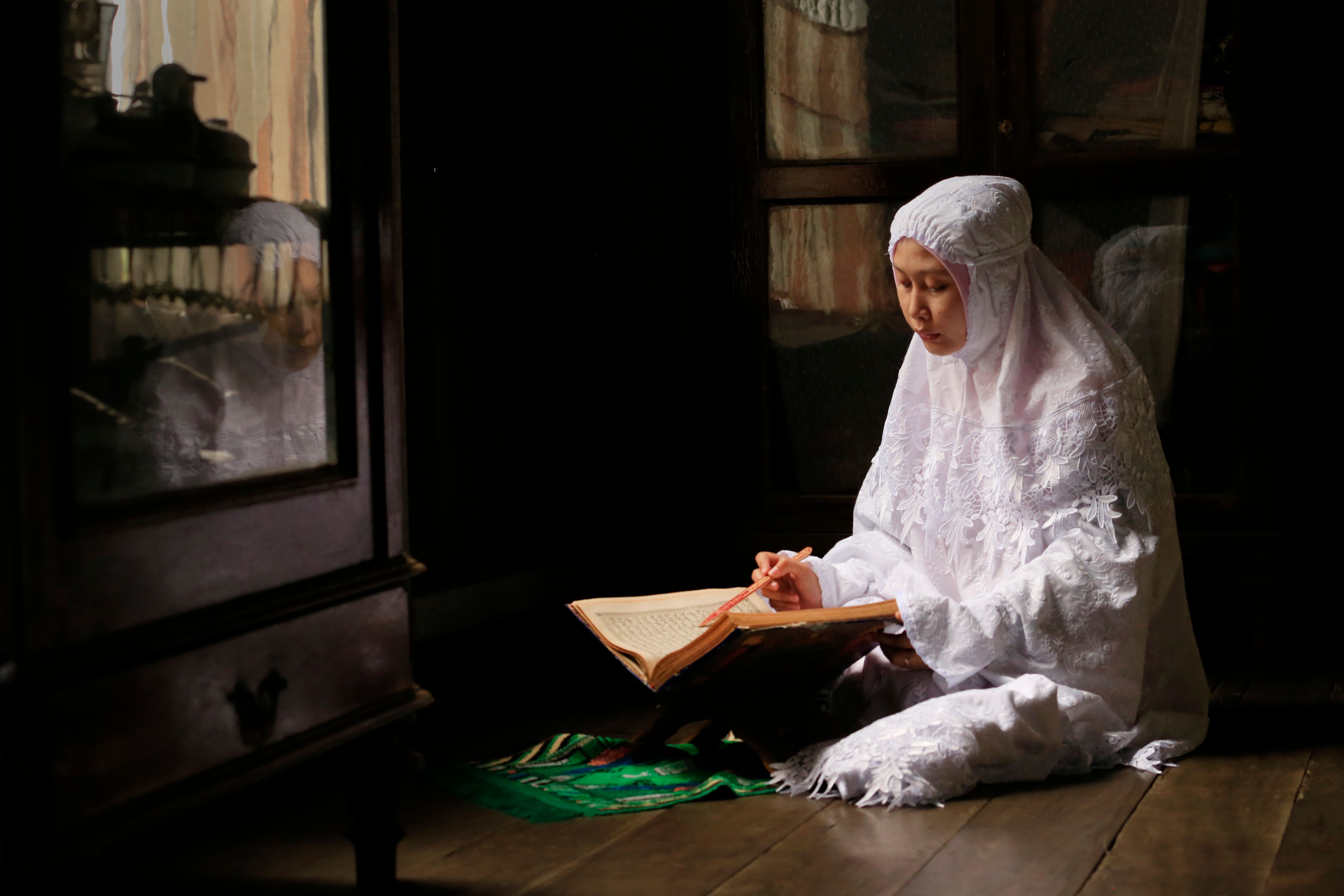 Young woman in traditional attire engaged in reading, creating a serene indoor scene.