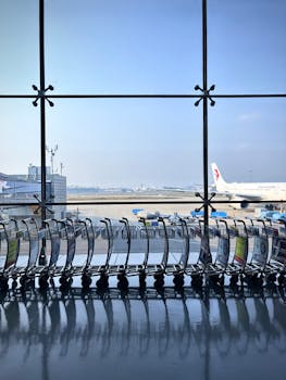Airport scene with lined trolleys and airplane at a sunny terminal window.