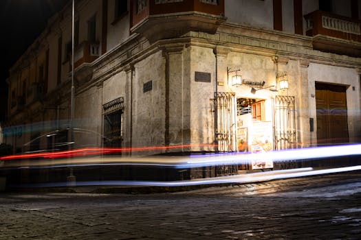 Long exposure captures moving lights against Arequipa's historic colonial architecture at night.