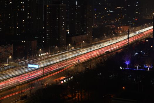 Aerial view of city traffic at night with vibrant light trails.