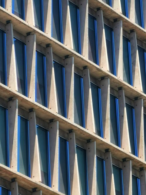 Free Angular facade of a modern building featuring striking geometric patterns and glass elements. Stock Photo