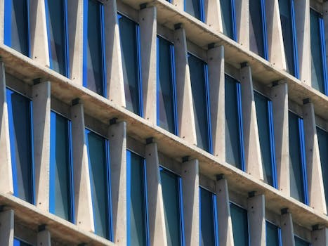Close-up of a modern building facade with blue-tinted windows and structural beams.