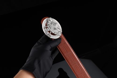Free Brown alligator leather belt with detailed silver buckle held by gloved hand. Stock Photo