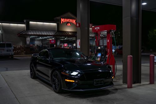 Free Sleek black sports car refueling at a gas station at night with Maverik signage. Stock Photo