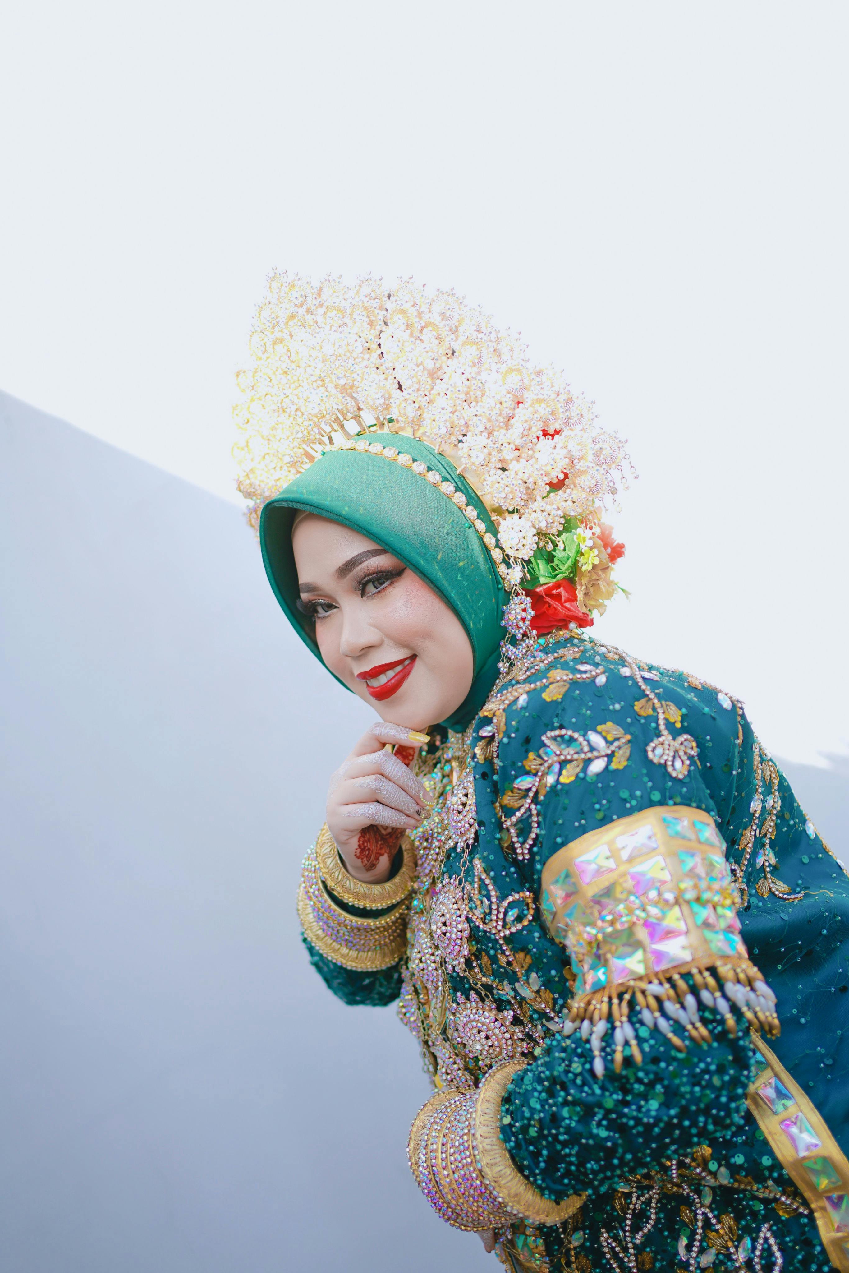 A woman in traditional Bugis bridal attire with intricate embroidery and vibrant colors.