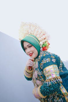 A woman in traditional Bugis bridal attire with intricate embroidery and vibrant colors.