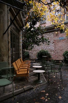 Charming outdoor café with wooden chairs and autumn leaves, perfect for relaxation.