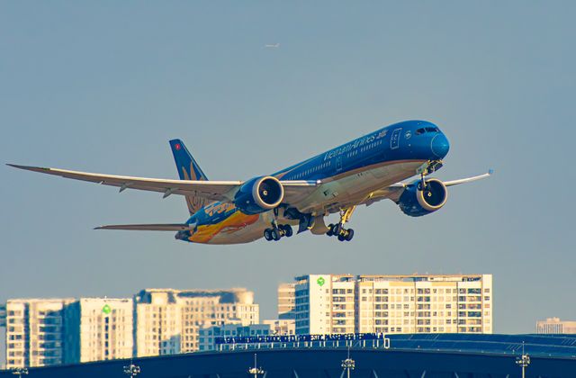 Vietnam Airlines plane taking off from Ho Chi Minh City airport with urban skyline background. — arriving in Ho Chi Minh City