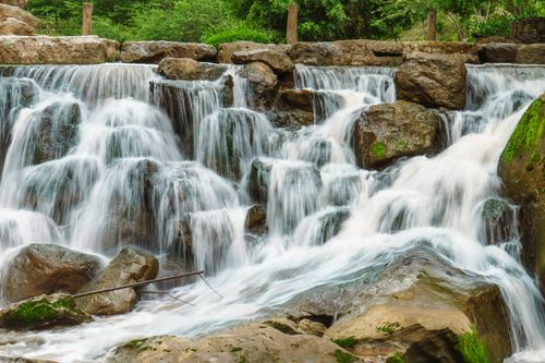 Free Serene waterfall cascading over rocks in a verdant forest setting, ideal for nature lovers. Stock Photo