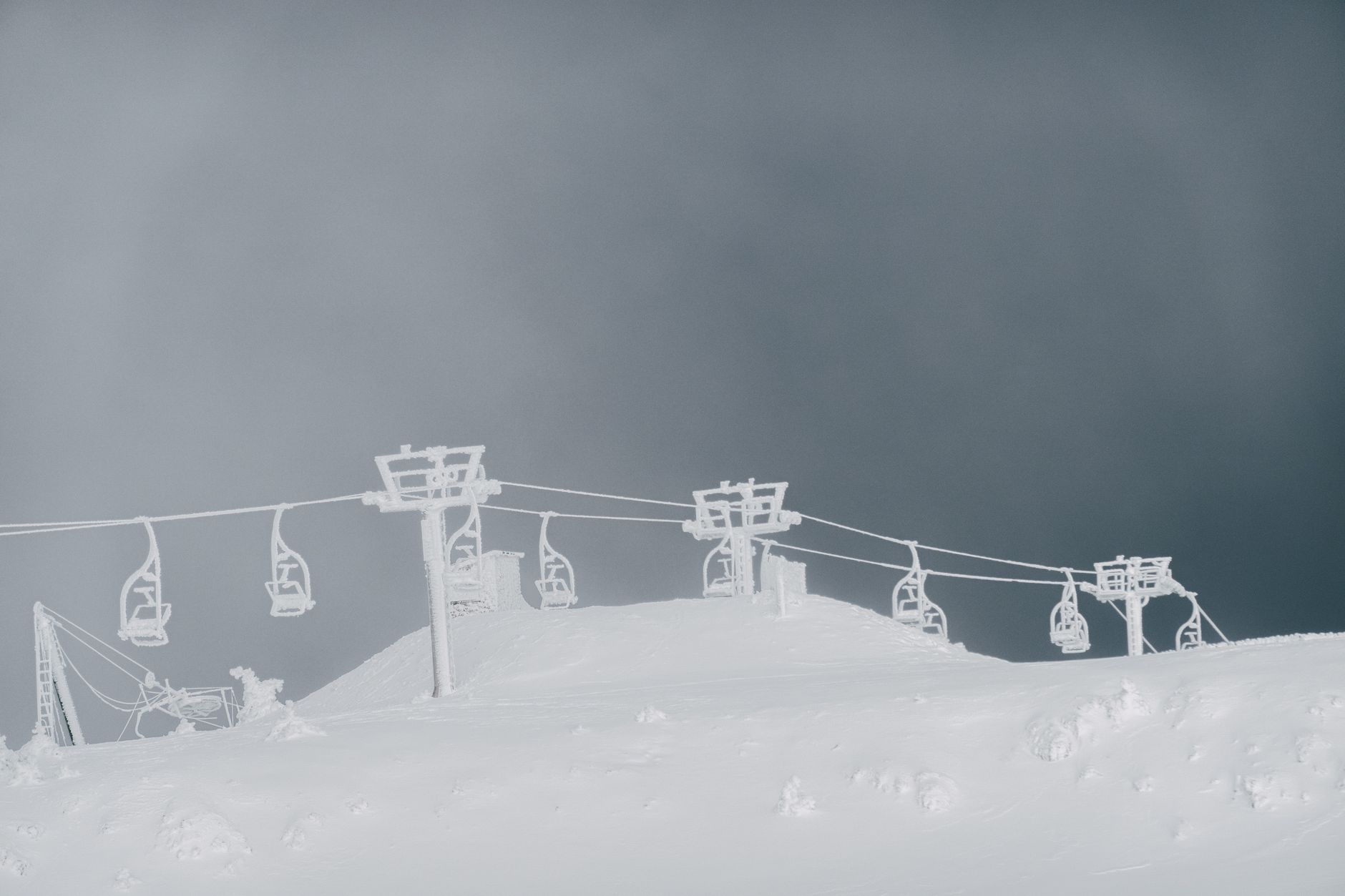 Snow-covered ski lift on a winter mountain, offering a serene and frosty view.