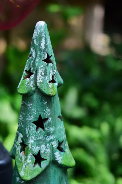 Free Close-up of a star-patterned ceramic Christmas tree outdoors with green foliage. Stock Photo