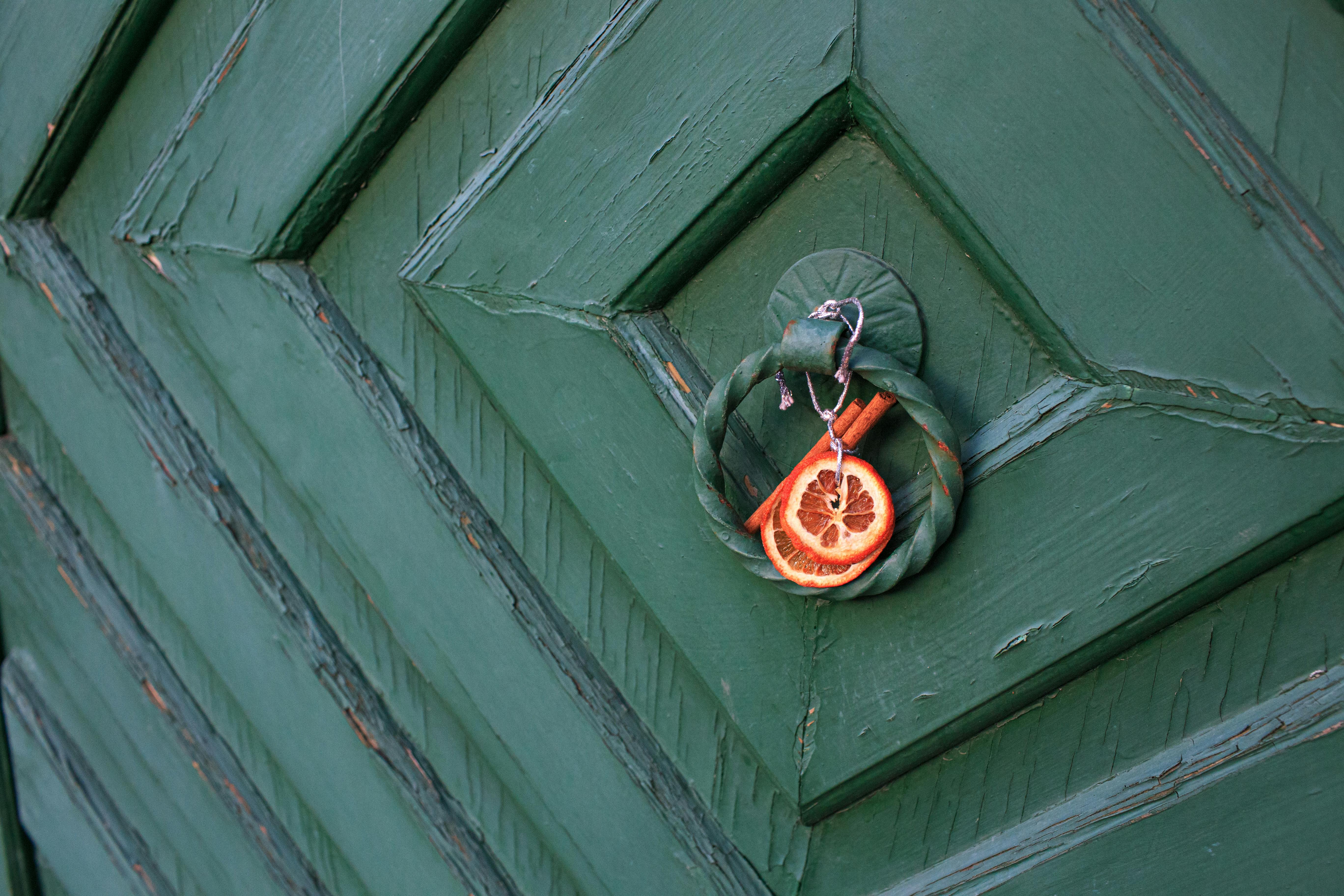 Green door with a dried citrus and cinnamon ornament, adding rustic charm.