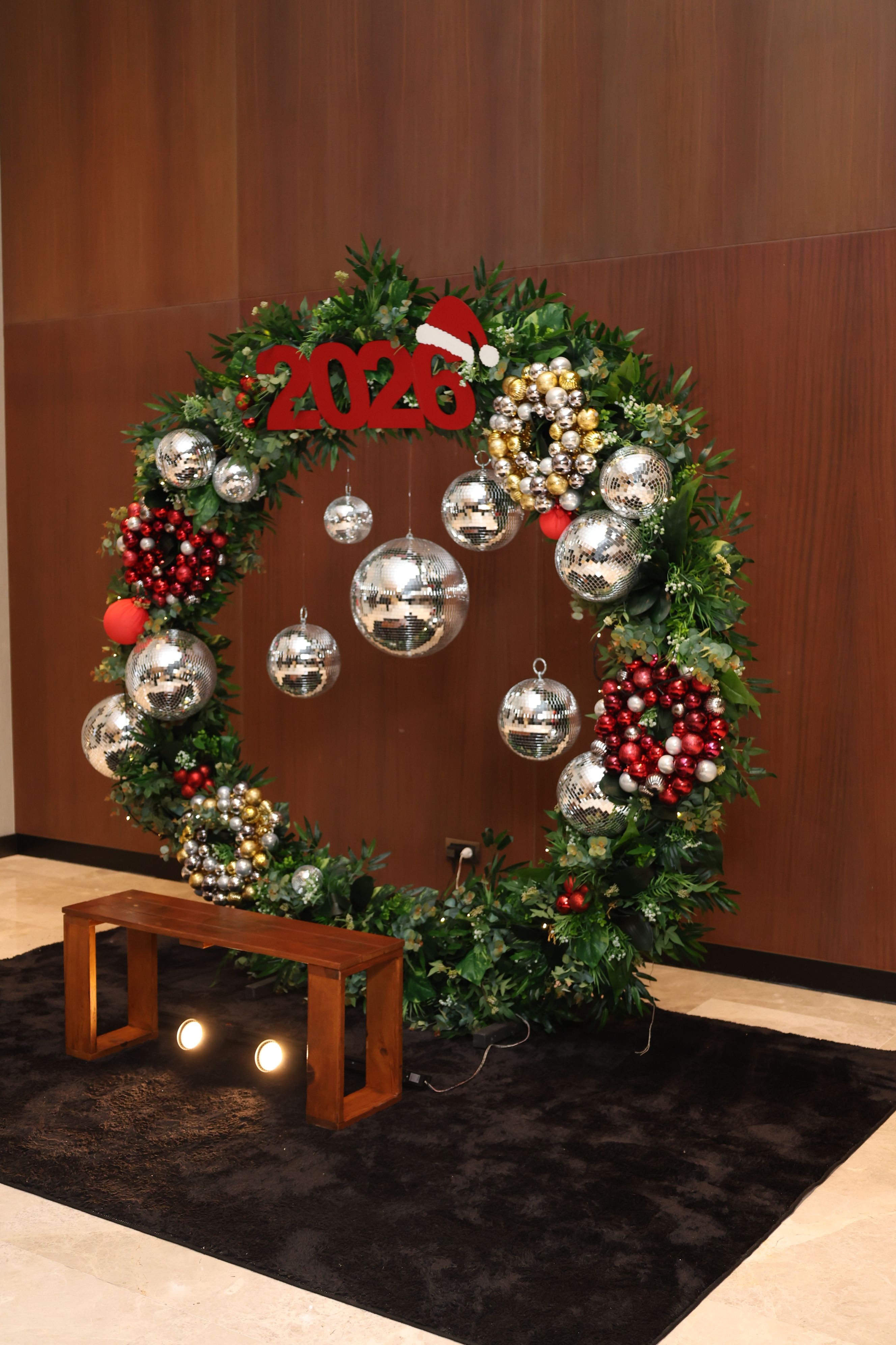 Large Christmas wreath with ornaments and 2023 text in a festive indoor setup.