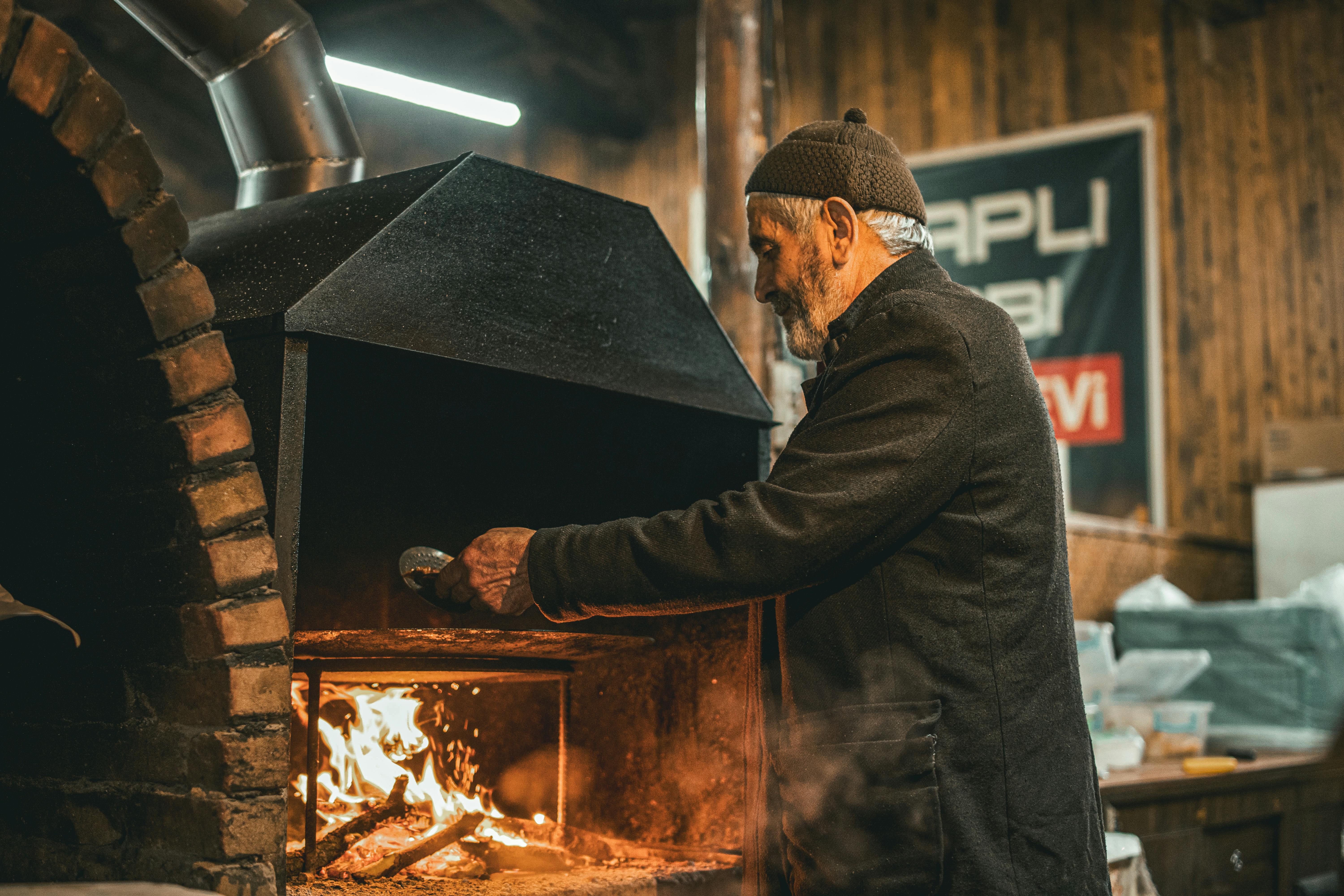 Un homme âgé utilise un four traditionnel dans une boulangerie turque chaleureuse, à Bursa, en Turquie.